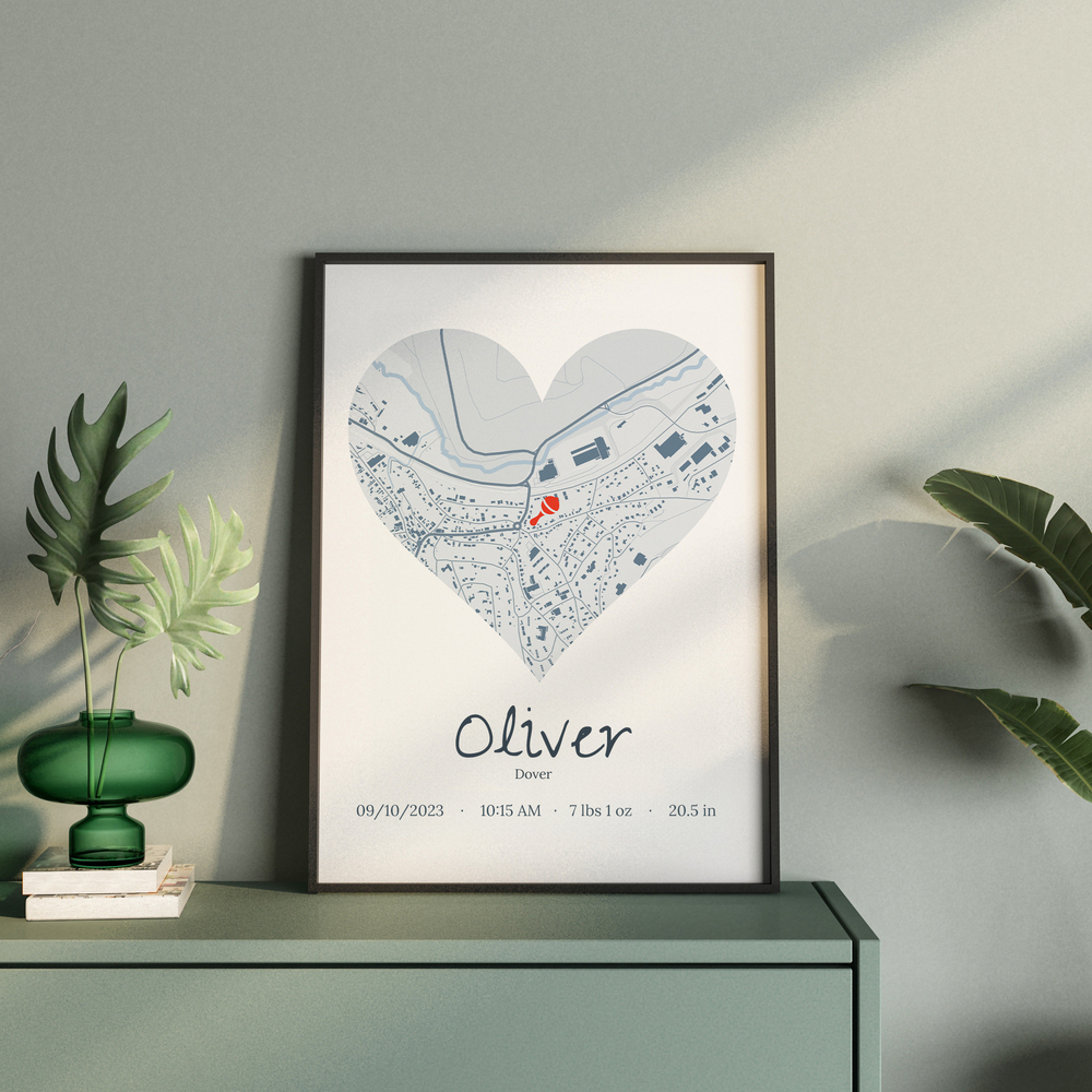 Heart-shaped birth map with baby stats in a black frame on a green cabinet, a keepsake gift for new parents