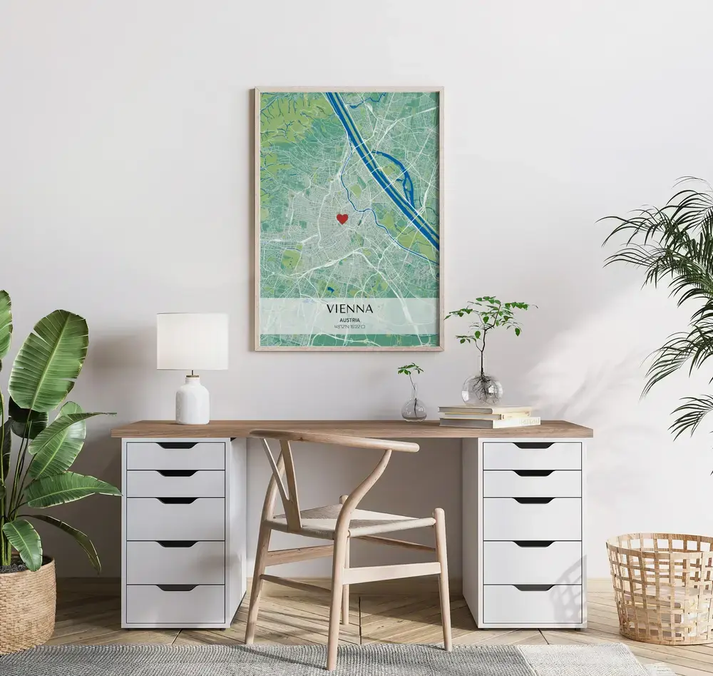 Green and blue city map poster with a light coordinate banner and heart marker, framed in wood above a desk