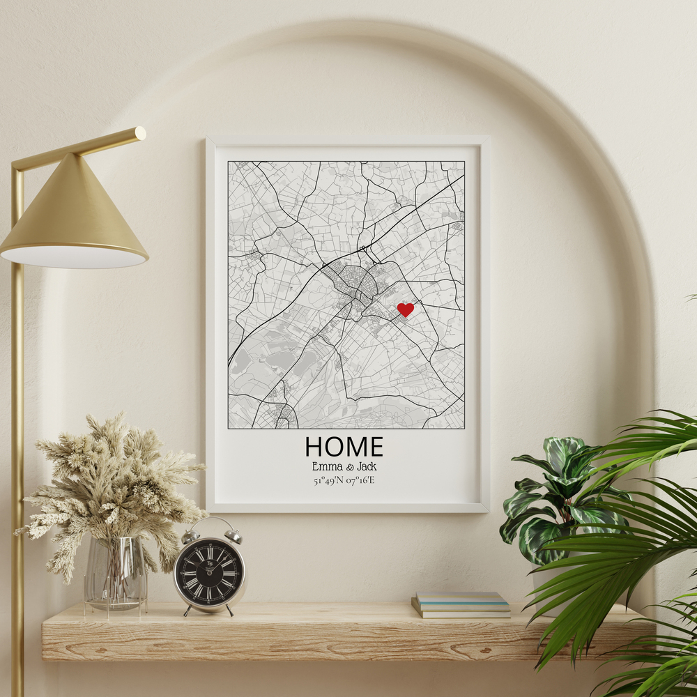 Custom home map with a red heart in a white frame, displayed in an arched wall niche beside a brass lamp