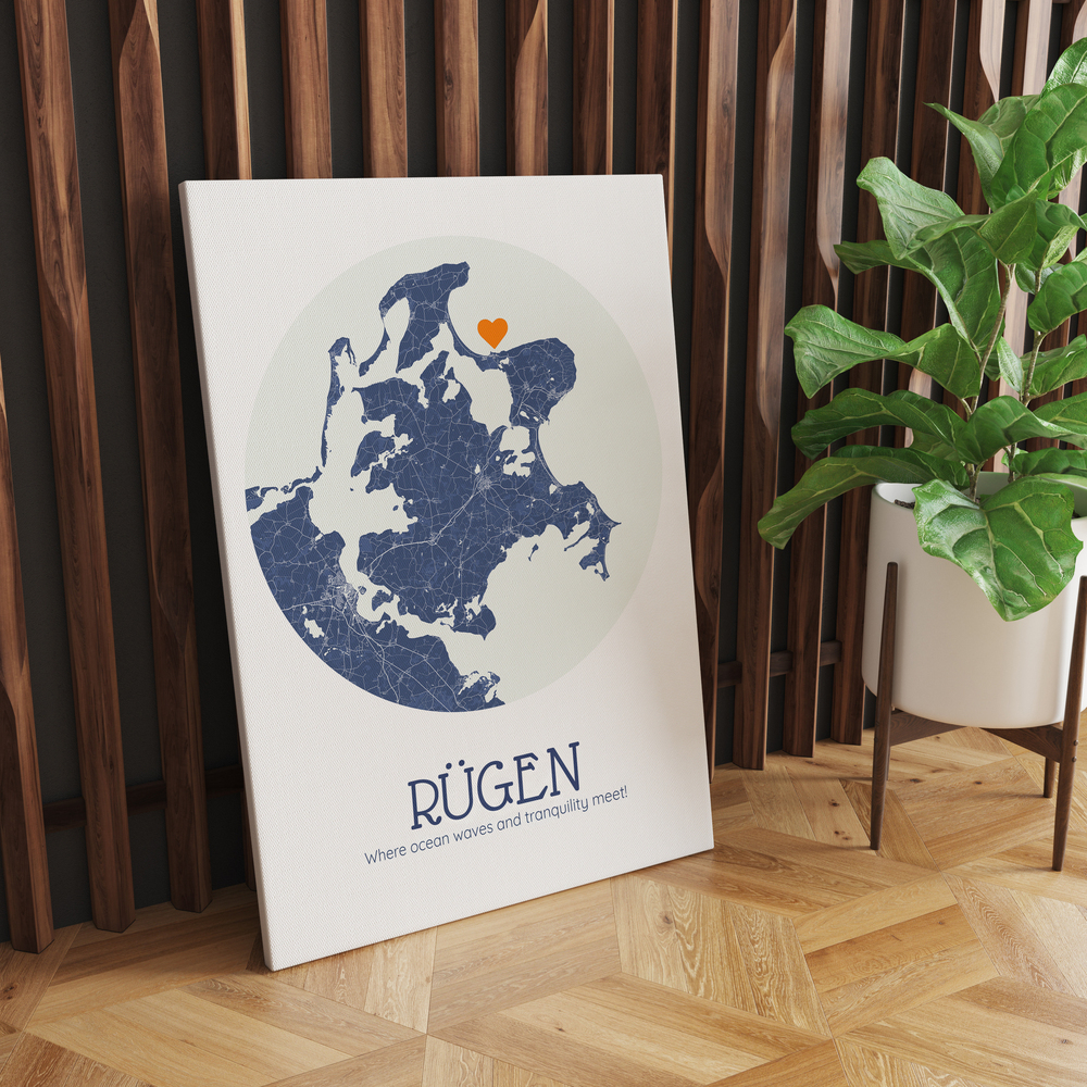 Circular Rügen map print with an orange heart, leaning against a wood slat wall beside a potted plant