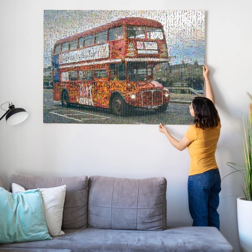 Photo mosaic of a red double-decker bus made of many small photos, being hung above a sofa